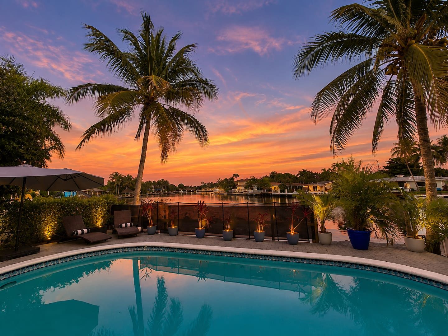 Sunset over the heated pool and canal at Mvillas, framed by palms