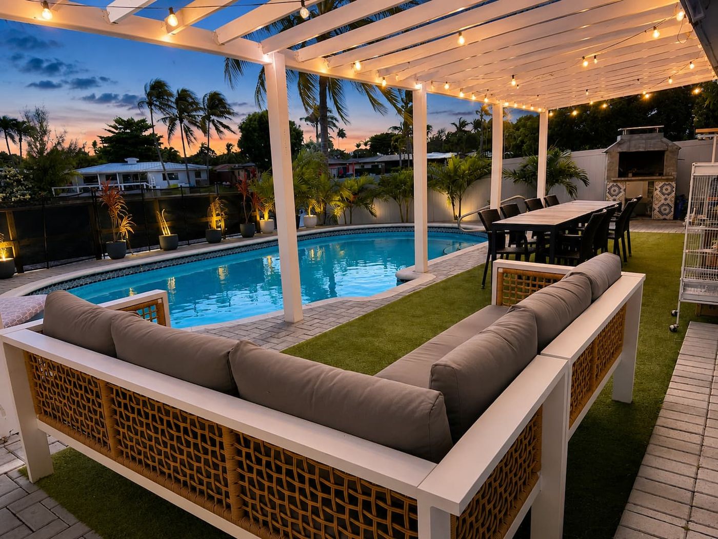Outdoor lounge and dining table by the pool at dusk